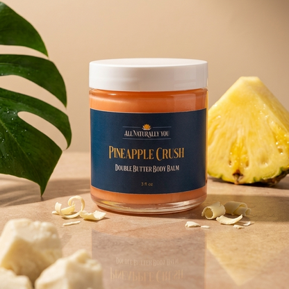 Jar of pineapple crush body balm on a wooden surface with a pineapple and leaves in the background.